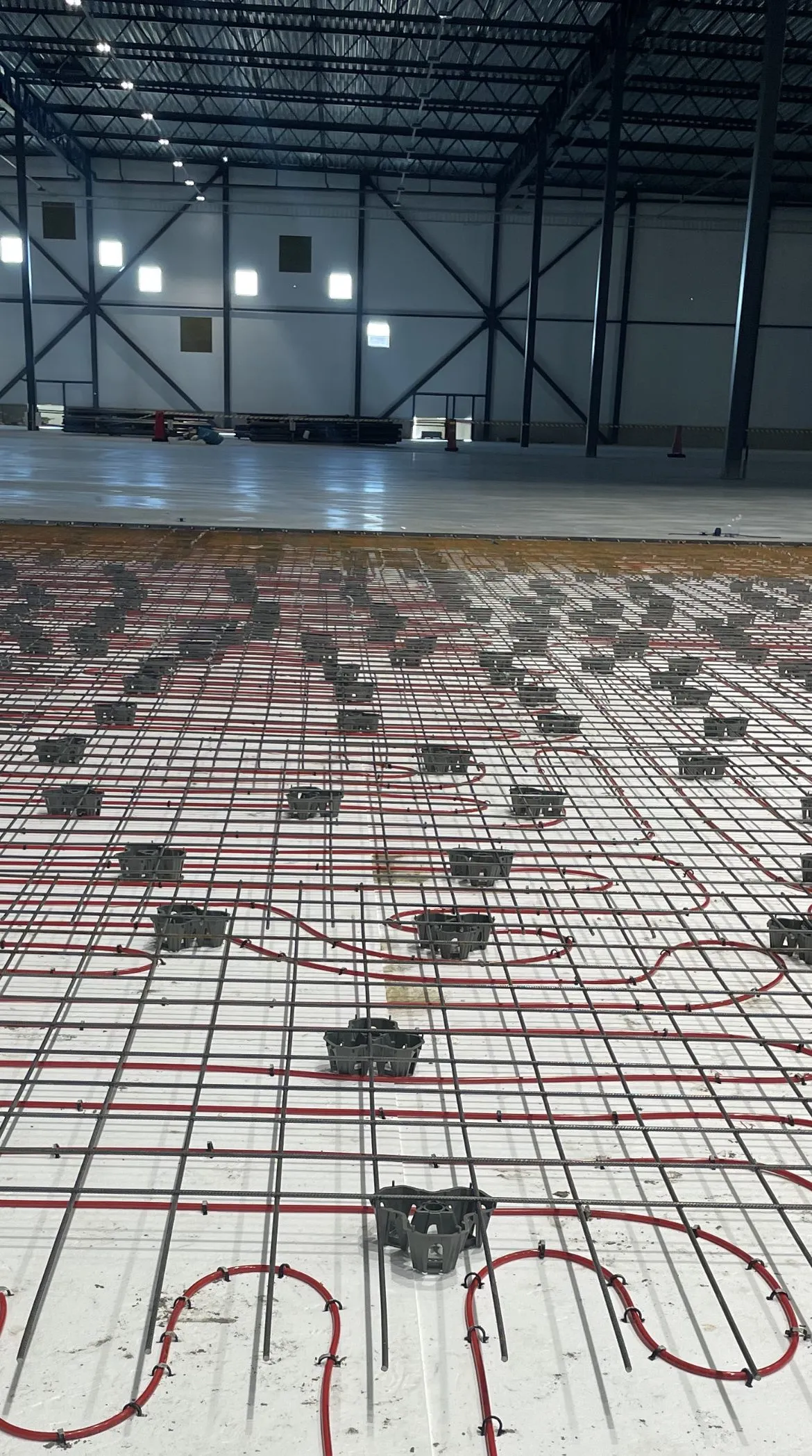 Long rows of heating pipes laid across a large hall floor